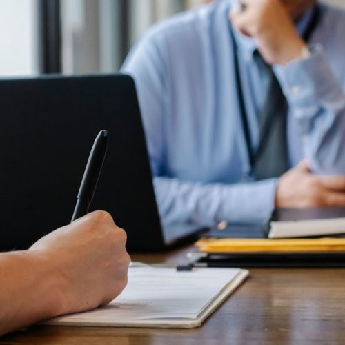 Crop anonymous female filling questionnaire when applying for job sitting in employer office